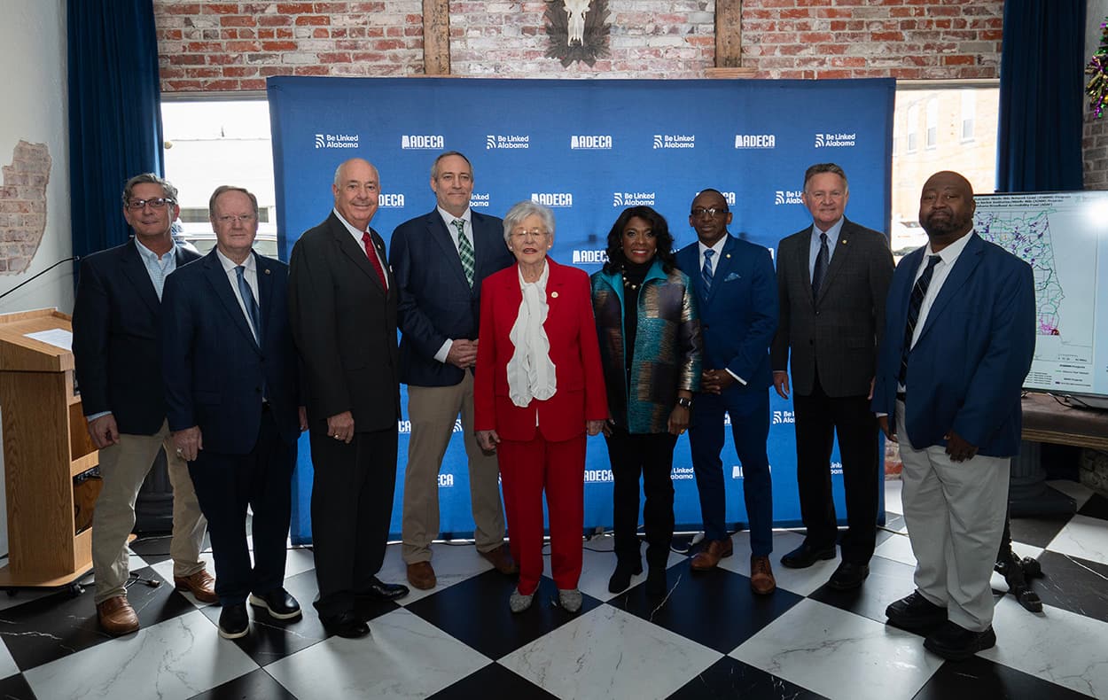 governor kay ivey featured with JMF's CEO Mike Francis, Marcus Holt, Vince Molyneux, and others from the State of Alabama in front of a backdrop